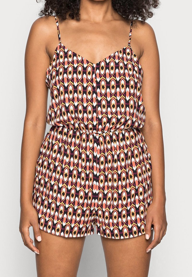 Combinaison à motifs avec un col en V, des bretelles fines, une taille élastique et un design géométrique en rouge, orange, blanc et noir.