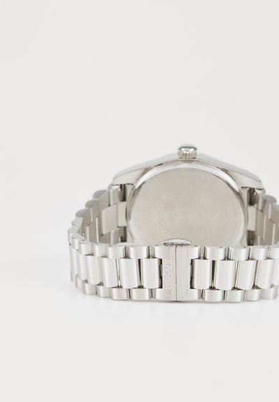 Montre en acier inoxydable avec un boîtier solide et un bracelet à maillons poli. Présente une couronne proéminente et le logo Versace sur le fermoir.