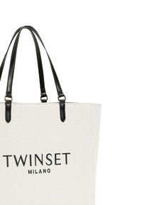 Kanvas bevásárlótáska fekete bőr fogantyúkkal. Elején a "TWINSET MILANO" felirat nagybetűkkel. Semleges krémszín, strukturált kialakítás.