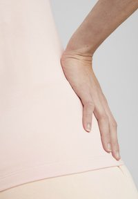 Lichtroze, nauwsluitende top gemaakt van zachte, rekbare stof, met een gladde textuur en versierd met subtiele stiksels langs de zoom.