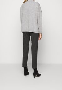 Lysegrå oversized sweater med ribkant, kombineret med mørkegrå skræddersyede bukser. Sorte ankelstøvler fuldender outfittet.