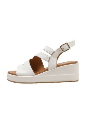 Sandales à talons compensés blanches en cuir, avec deux sangles réglables, un design ouvert à l'avant et une semelle texturée. Caractéristiques d'une accent métallique sur la boucle.