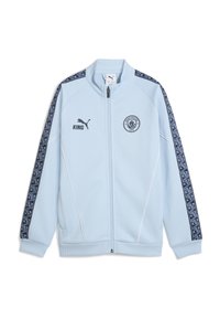 Ljusblå zip-up jacka med vita accenter, med en Manchester City-logotyp och svarta mönstrade sidosträck, tillverkad av ett slätt tyg.