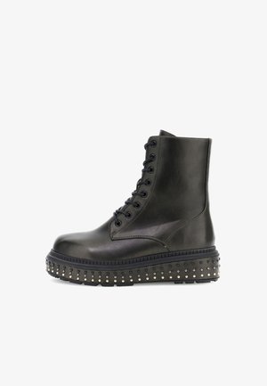 Zwarte leren enkelboot met vetersluiting, ronde neus en platformzool versierd met kleine gouden studs langs de rand.