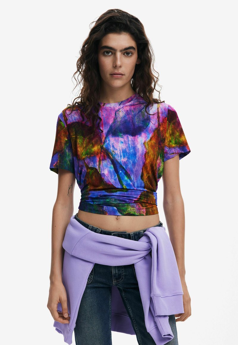 Crop top con un motivo vivace e multicolore di viola, verde e blu. Tessuto morbido con scollatura rotonda e maniche corte.