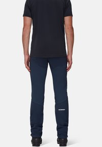 Pantaloni softshell blu navy con ginocchia rinforzate e vestibilità slim. Presentano un logo sulla parte inferiore della gamba e polsini elastici per una vestibilità sicura.