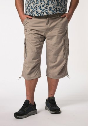 Shorts cargo beiges avec poches latérales et ourlets à cordon de serrage, associés à des chaussures de sport noires. Le tissu semble léger et durable.
