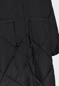 Czarna pikowana kurtka z dwoma kieszeniami, zapięciem na napy i gładką fakturą, zaprojektowana w diamentowy wzór z minimalnymi akcentami.