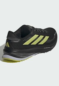 Black running shoe with yellow Adidas stripes, Gore-Tex label, and "Dreamstride+" sole, angled to show outer side and heel.