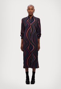 Pikk, nööbitav kleit tumedast kangast laineliste, mitmevärviliste triipudega. See on disainitud krae ja vabade varrukatega mugavuse tagamiseks.