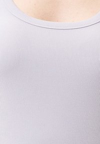 Jasnoszara, żeberkowana koszulka na ramiączkach z okrągłym dekoltem. Miękki, elastyczny materiał ma delikatne pionowe linie na tkaninie.