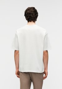 Κοντομάνικο t-shirt από βαμβάκι ανοιχτού κρεμ χρώματος, με κλασικό στρογγυλό λαιμό και άνετη εφαρμογή. Ομαλή υφή, μινιμαλιστικός σχεδιασμός.