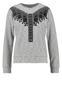 Felpa grigia realizzata in tessuto texture, con un motivo geometrico ricamato nero sul petto e un collo rotondo. Maniche lunghe.