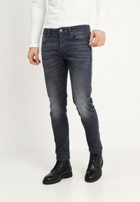 Mörkgrå skinny jeans med subtila blekningar, femfickorsdesign och en enda framknapp. Kombinerat med svarta snörskor.