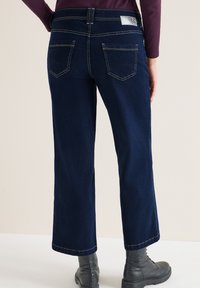 Donkerblauwe denim jeans met een rechte pijp, voorzien van een hoge tailleband, contrasterende stiksels en twee achterzakken.