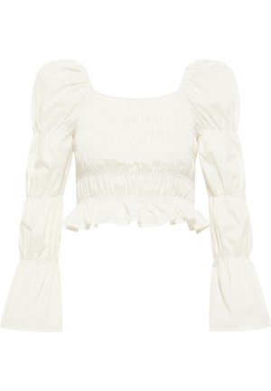 Top corto blanco con escote cuadrado, mangas abullonadas y detalles fruncidos. Presenta un dobladillo con volantes y una textura de tela suave y lisa.