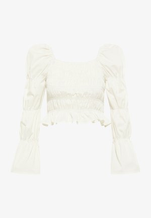 Top corto blanco con escote cuadrado, mangas abullonadas y detalles fruncidos. Presenta un dobladillo con volantes y una textura de tela suave y lisa.