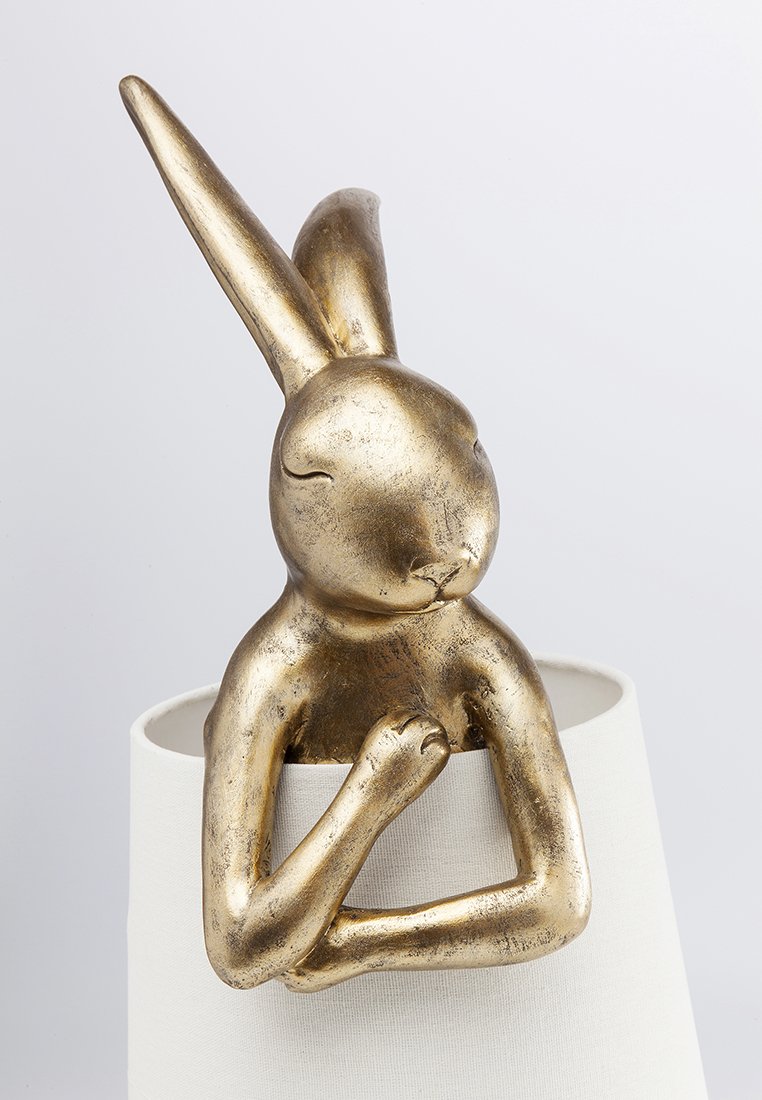 Goldfarbene Kaninchen-Skulptur mit glänzender, metallischer Oberfläche. Sie hat lange Ohren und steht auf einem weißen zylindrischen Sockel.