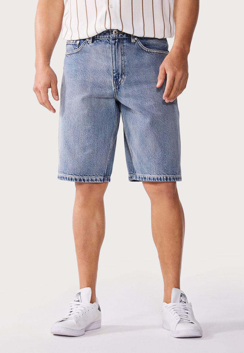 Lichtblauwe denimshorts met een rechte snit, met een denimstructuur, vijf zakken en een rafelige zoom. Gecombineerd met witte sneakers.