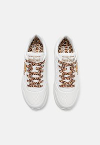 Weiße Sneaker mit Leopardenmuster-Laces und Innensohle. Merkmale sind glatte und perforierte Texturen sowie goldene Branding-Akzente auf der Zunge.