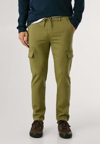 Olivengrøn cargobukser med to sidelommer, snøre i taljen, slim fit og en glat tekstur, parret med mørkebrun sneakers.