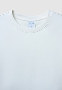 T-shirt bianca a girocollo realizzata in morbido cotone. Presenta un'etichetta con il marchio "CALLIOPE" e la taglia "L" all'interno del collo.