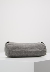 Gray fabric pencil case with a cylindrical shape, textured surface, and zipper closure. Features black hardware accents.
