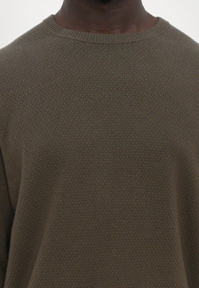 Olive rohelise värvi kudum, millel on struktuurne muster, ümmarguse kaeluse ja soonikust varrukaotstega. Suurendatud vaade, keskendudes kanga detailidele.