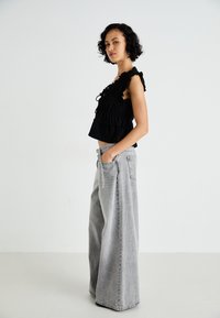 Musthave mustripot top mustele piduritega, mis on paaritatud laia jalaga heledate hallide teksadega, mis on varustatud taskutega ja millel on mugav lõige.