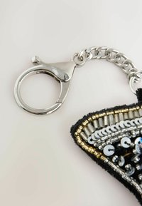 Silver lobster clasp attached to a chain, with black fabric featuring metallic beading and sequins in gold and silver tones.