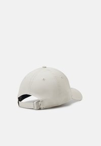 Casquette de baseball en coton beige avec une visière incurvée, une sangle ajustable à l'arrière et des accents de couture visibles. Design épuré sans motifs.