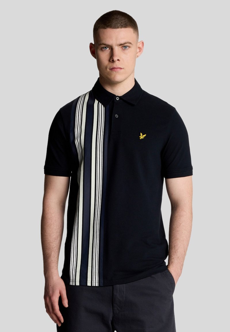 Polo shirt di colore blu navy con motivo a strisce verticali in bianco e blu scuro. Presenta un colletto e un piccolo logo giallo sul petto. Maniche corte.