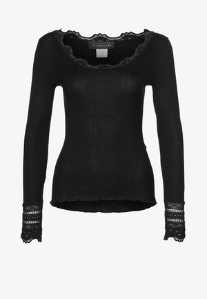 Top nero a maniche lunghe con coste, dotato di un collo in pizzo a zig zag e dettagli in pizzo ai polsini. Design aderente con orlo leggermente asimmetrico.