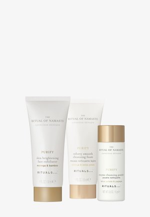 Drie huidverzorgingsproducten in witte tubes en een pot, met gouden accenten. Tekst bevat onder andere "Purify" en ingrediënten zoals moringa en lotusblaadjes.