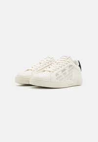 Vita lädersneakers med en texturerad ovandel, perforerade detaljer, kontrasterande svart hälflik och platta snören. Gummisula.