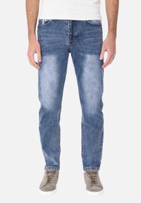 Jeans in denim azzurro chiaro con taglio dritto, zone scolorite, cinque tasche e dettagli cuciti, abbinati a sneakers grigie.