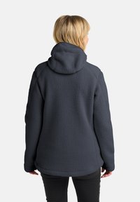 Dunkelgraue Fleecejacke mit strukturierter Oberfläche, ausgestattet mit Kapuze, langen Ärmeln und einem entspannten Schnitt. Keine sichtbaren Beschläge oder Verzierungen.