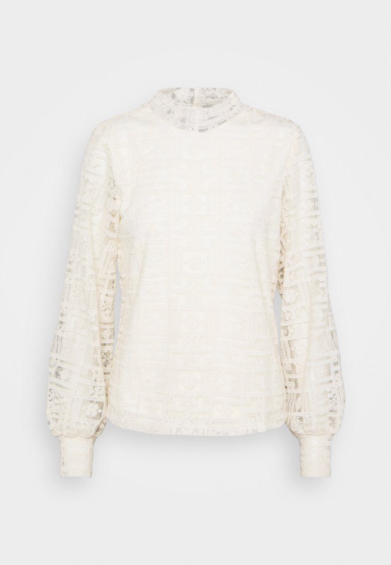 Blouse en dentelle couleur blanc cassé avec manches longues bouffantes, col montant, texture à motifs complexes et corsage ajusté.