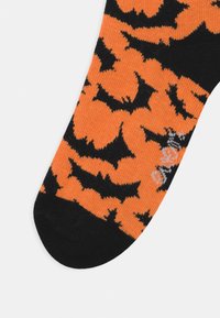 Orange socks featuring a pattern of black bats, with a contrasting black toe section. Made from soft, stretchy fabric.