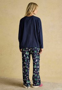 Tumedast pikkade varrukatega särk, millele on kombineeritud piduliku mustriga ööpüksid, millel on puud ja talvised stseenid. Pehme kangas ja vabalt langev lõige.