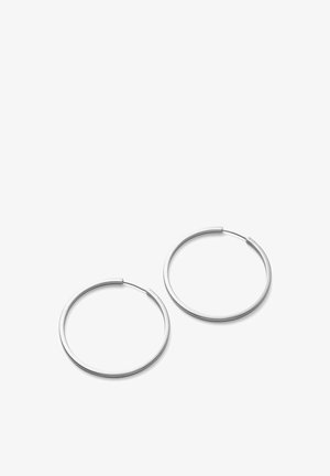 Paire de boucles d'oreilles en forme de cerceau fines en métal argenté avec fermoirs à charnière sur fond blanc.