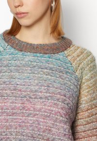 Maglione lavorato a maglia multicolore con un design testurizzato, caratterizzato da un colletto a coste e maniche contrastanti in tonalità pastello.