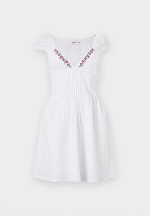 Valge lühike kleit puffyvarrukatega, rõngastega tagakülg, volditud eesmine osa ja lilleseemne tikand sügava V-kaeluse ääres.