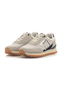 Zapatillas beige con materiales de lona y gamuza, con un acento en azul marino, puntera redonda y suela de goma texturizada con acabado en color caucho.