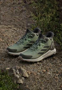 Groene wandelschoenen met een bovenwerk van mesh en synthetisch materiaal, voorzien van zwarte accenten, een gestructureerde zool en een versterkte teenkap. Geschikt voor buitenactiviteiten.