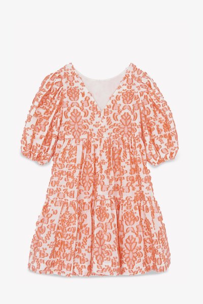 Robe pêche brodée de fleurs avec un décolleté en V et de courtes manches bouffantes. Tissu texturé avec une jupe à volants et des détails froncés.