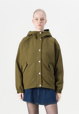Veste à capuche vert olive avec une coupe décontractée, présentant des boutons-pression et des poches latérales, associée à une jupe en denim. Texture de tissu lisse.
