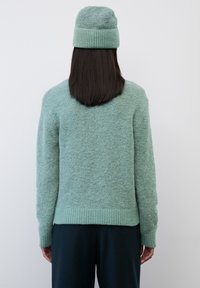 Set aus Pullover und Mütze aus weicher mintgrüner Wolle. Der Pullover hat einen gerippten Saum und Bündchen; flauschige Textur. Lässige Passform.