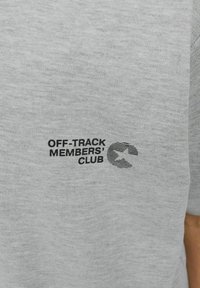 Hallhallane puuvillane T-särk, millel on must graafiline logo ja tekst "OFF-TRACK MEMBERS' CLUB" koos stiliseeritud ringikujulise kujundusega.