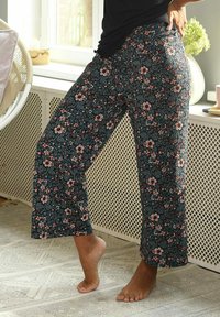 Floral patterned, dark fabric trousers with an elastic waistband. Loose fit with wide legs and a cropped length, featuring a variety of small flowers.